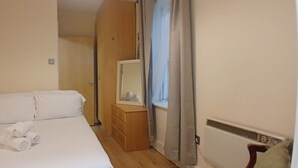 A hotel room with a bed, a wooden dresser, a mirror, and a window with curtains. - Modern 3BDR Home Heart of The Liberties (Dublin)