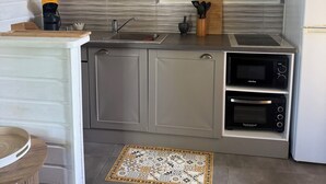 Une cuisine moderne équipée d’un four à micro-ondes, d’un four et d’un évier intégrés. On y trouve également une machine à café, un bloc à couteaux et un miroir décoratif accroché au mur.