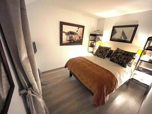 A bedroom with a bed, a nightstand, a lamp, and two wall-mounted pictures. - A gem in the heart of the city (Quimper)