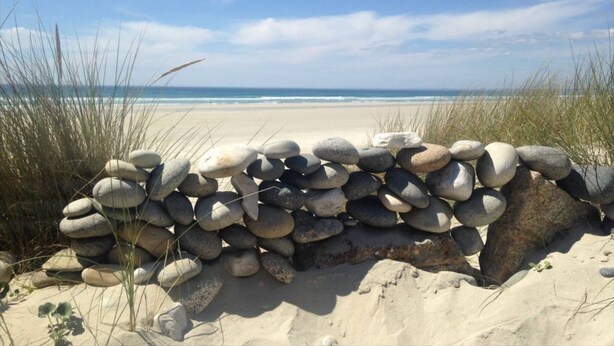 Ein Strand mit einer Steinmauer und Meerblick.