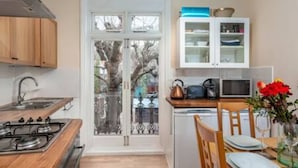Une cuisine dotée de meubles en bois, d’une cuisinière, d’un four à micro-ondes et d’un coin repas avec une table mise pour deux personnes.