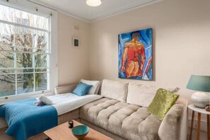 Een kamer met een bed, een bank, een tafel en een schilderij aan de muur.