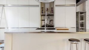 A modern kitchen with a central island, bar stools, and a built-in wine rack. - Experience London in Amazing Reconverted Gin House (London)