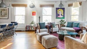 A modern living room with a sofa, ottomans, a coffee table, and a bookshelf. - Experience London in Amazing Reconverted Gin House (London)