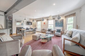 A spacious living room with a fireplace, modern furniture, and large windows. - Experience London in Amazing Reconverted Gin House (London)
