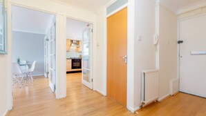 Eine moderne Wohnung mit Holzboden, einer Küche mit weißen Schränken und einem Essbereich mit Tisch und Stühlen.