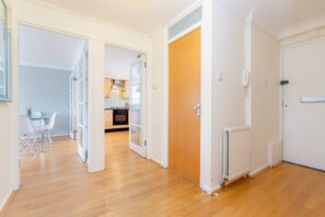 A modern apartment with a wooden floor, a kitchen with white cabinets, and a dining area with a table and chairs. - Bright 2bed Flat in Holland Park-notting Hill (London)