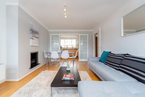 Un salon moderne avec un canapé, une table basse et une cheminée. On aperçoit à l’arrière-plan un coin repas avec des chaises et une table.