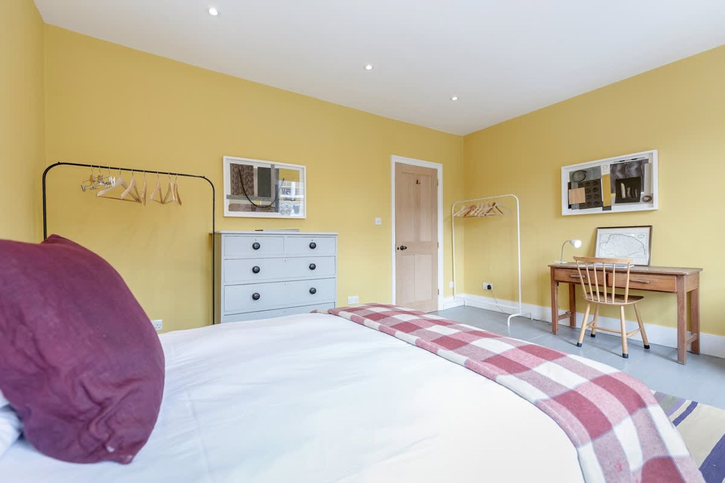 A bedroom with a bed, a desk, and a chair. There are two doors, one leading to a bathroom and another to a closet.