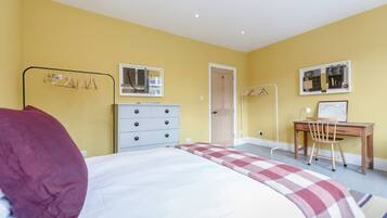 A bedroom with a bed, a desk, and a chair. There are two doors, one leading to a bathroom and another to a closet.