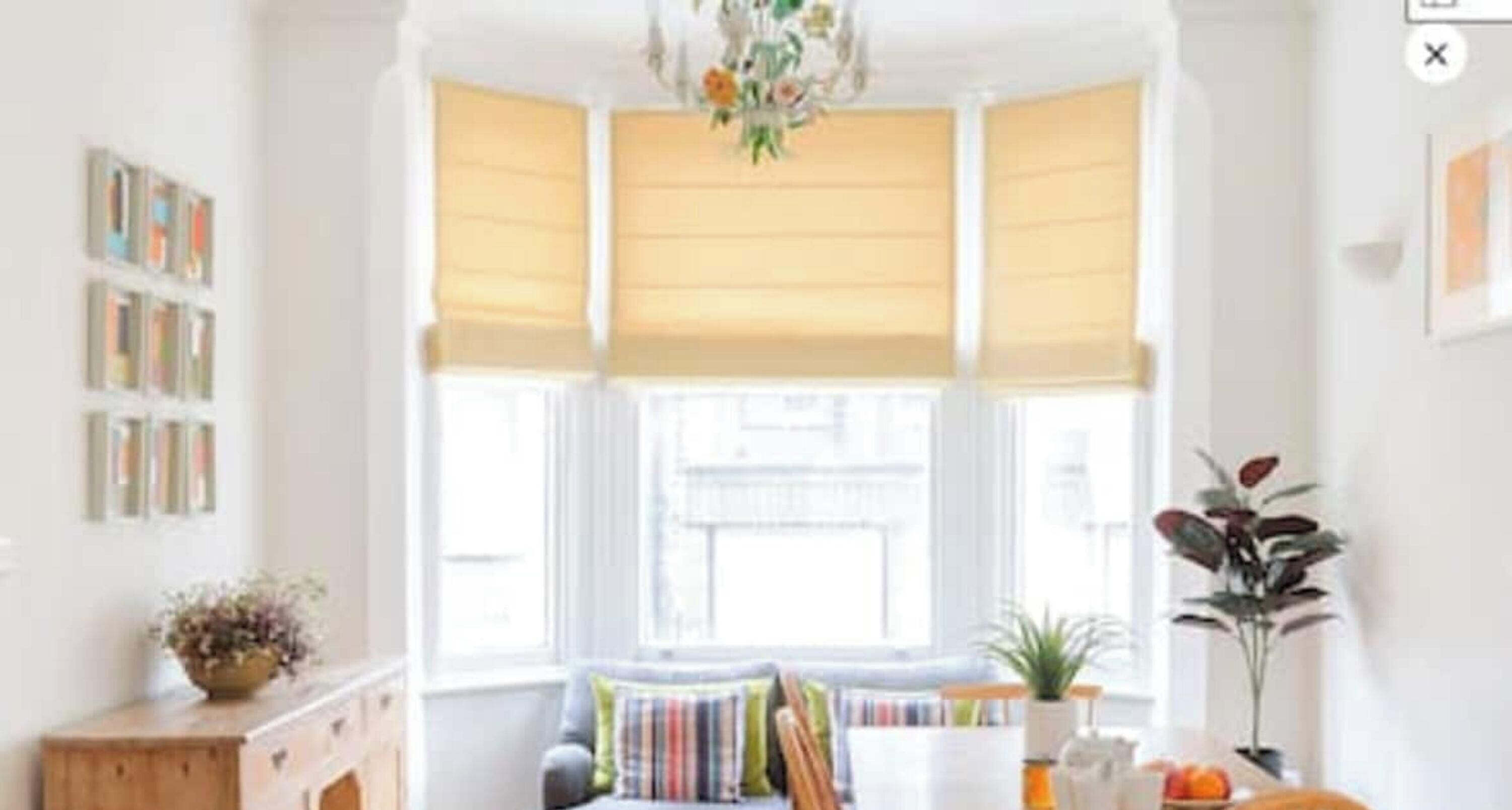A bright room with a window, a sofa, a table with a plant, and a cabinet.