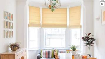A bright room with a window, a sofa, a table with a plant, and a cabinet.