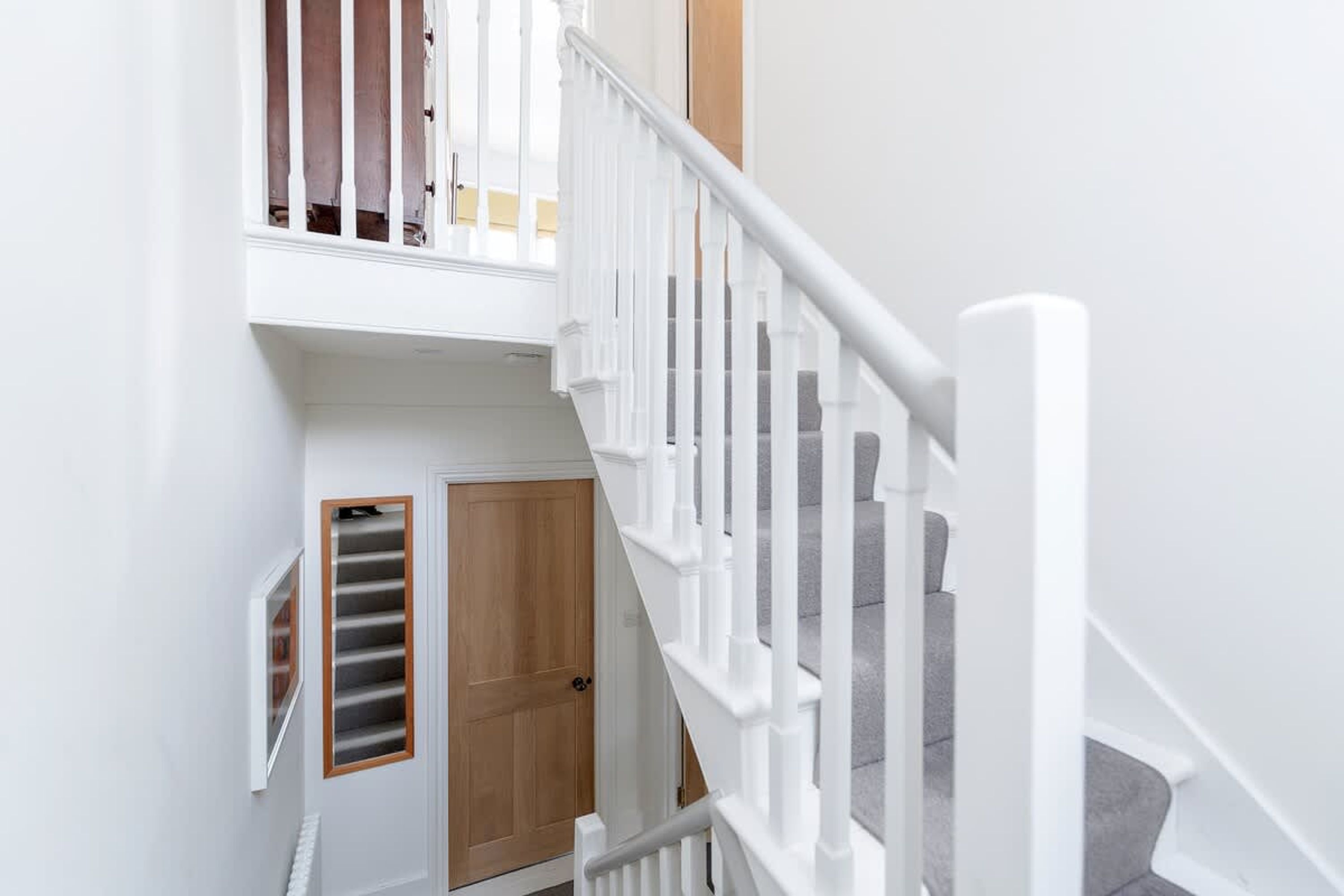 A staircase with white railings and a wooden door at the bottom.