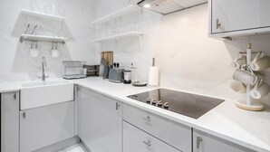 A modern kitchen with white cabinetry, a stainless steel sink, and a built-in oven. - Beautiful Refurbished 2bed 2bath Next to Hyde Park (London)