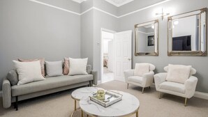 A living room with a grey sofa, two white armchairs, a marble coffee table, and two large mirrors on the wall. - Beautiful Refurbished 2bed 2bath Next to Hyde Park (London)