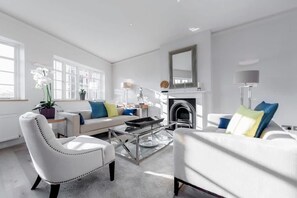 A modern living room with a fireplace, white sofas, and a coffee table. - Modern Stylish 2bed 2bath Close to Kings Road (London)