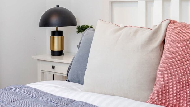 A neatly made bed with a blue quilt, a white pillow, and a red patterned pillow. - Spacious 2bed in top Location Holland Park-n Hill (London)