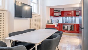 Una cocina moderna con armarios rojos, un refrigerador de acero inoxidable y un televisor de pantalla plana montado en la pared.