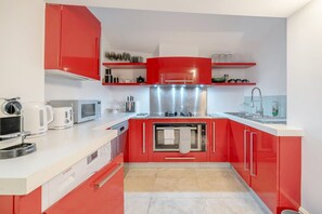 A compact kitchen with red cabinets, a microwave, a toaster, and a sink. - Spacious Modern 2bed 2 5bath in Pimlico-victoria (London)