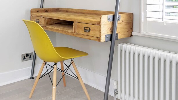 A room with a wooden desk with drawers, a yellow chair, and a radiator. - Stylish 3-floor 3bed Home With Garden Near River (London)