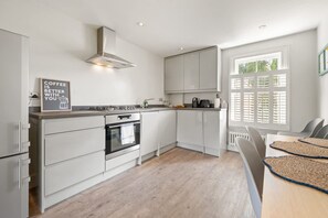 A modern kitchen with white cabinetry, a built-in oven, and a window with blinds. - Fabulous All-new 2bed-2bath - Vauxhall Near River (London)