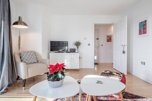 Ein modernes Wohnzimmer mit einer Couch, einem Couchtisch und einem Fernseher im Hintergrund.