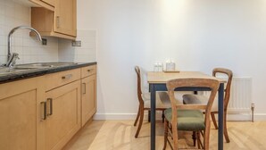 Une cuisine avec des meubles de rangement en bois, un plan de travail noir et une table à manger avec des chaises.