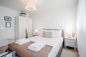 Ein ordentlich eingerichtetes Hotelzimmer mit Bett, Nachttischen, einem Kleiderschrank und einer Lampe.
