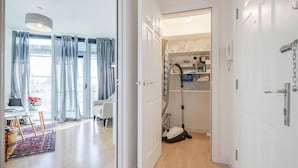 Une chambre d’hôtel moderne dotée d’une grande fenêtre, d’un coin repas avec une table et des chaises, et d’un placard visible avec des étagères.
