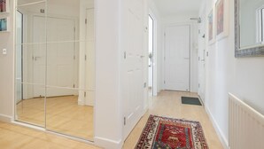 Un couloir avec une cloison en verre, des portes blanches, un tapis à motifs et un radiateur.