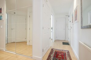 Un couloir avec une cloison en verre, des portes blanches, un tapis à motifs et un radiateur.