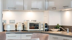 A modern kitchen with white cabinets, a built-in microwave, a toaster, and a sink with a plant on the counter. - Luxury and Quiet Oasis in London (London)