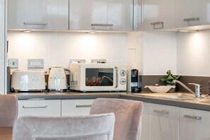 A modern kitchen with white cabinets, a built-in microwave, a toaster, and a sink with a plant on the counter. - Luxury and Quiet Oasis in London (London)