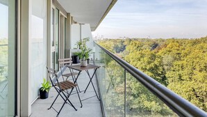 A balcony with a table and chairs, potted plants, and a view of a forested area. - Luxury and Quiet Oasis in London (London)