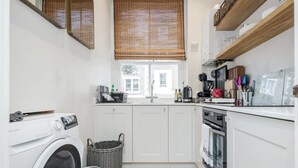 A compact kitchen with a washing machine, a sink, and a stove. - Charming Spacious 1bed Near Portobello Rd N Hill (London)