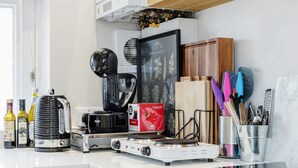 A modern kitchen with white cabinets, a built-in oven, a coffee maker, and various kitchen utensils. - Charming Spacious 1bed Near Portobello Rd N Hill (London)