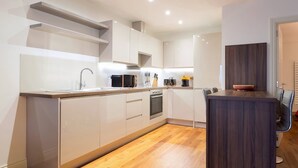 Una cocina moderna con armarios blancos, encimera de madera y horno empotrado.
