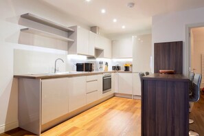 Eine moderne Küche mit weißen Schränken, einer Holz Arbeitsplatte und einem eingebauten Ofen.