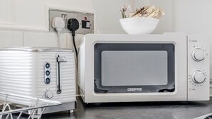 A kitchen with a white microwave, a toaster, and a dish rack. - Unbeatable Location in Camden-spacious Studio Flat (London)