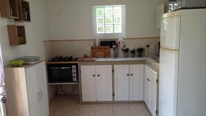 Eine Küche mit weißen Schränken, einem Herd, einem Backofen, einem Fenster und einem Kühlschrank.
