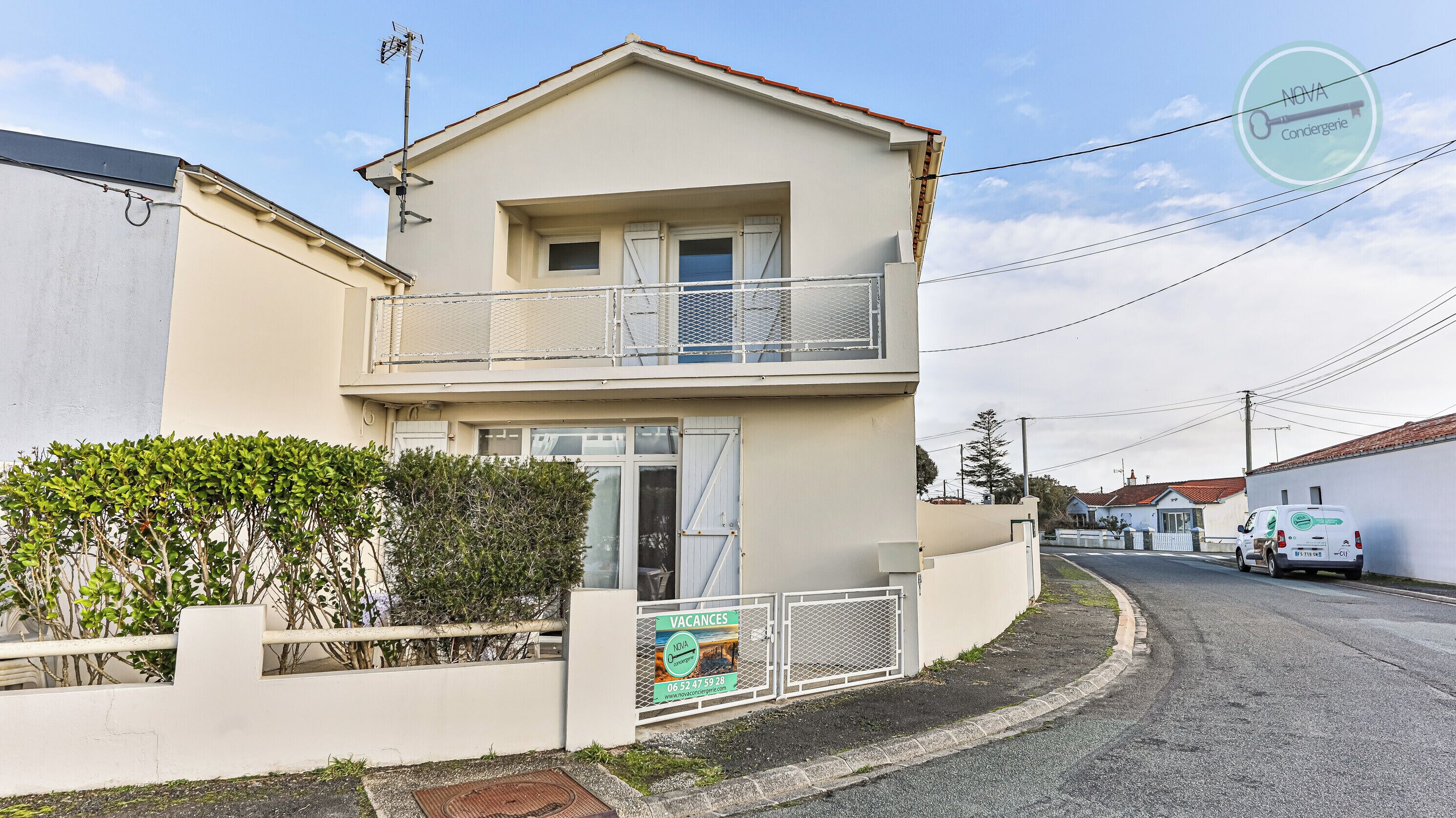 Un immeuble de deux étages doté d’un balcon, d’une enseigne indiquant qu’il y a des logements disponibles, et d’un fourgon stationné.