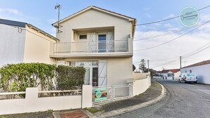 A two-story building with a balcony, a sign advertising vacancies, and a parked van. - La Maison du Soleil Sion sur l'océan (Saint-Hilaire-de-Riez)