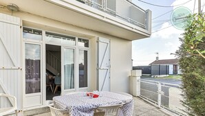 A balcony with a table and chairs, a white fence, and a building with a balcony. - La Maison du Soleil Sion sur l'océan (Saint-Hilaire-de-Riez)