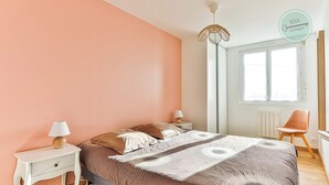 A bedroom with a bed, bedside tables, a lamp, a chair, and a window. - La Maison du Soleil Sion sur l'océan (Saint-Hilaire-de-Riez)