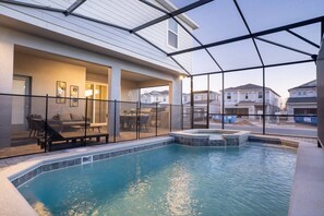 Ein Hallenbad mit Glasverkleidung, eine Terrasse mit Sitzgelegenheiten und Blick auf benachbarte Häuser.