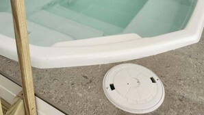 Un jacuzzi rectangular con interior blanco y exterior gris, rodeado de baldosas grises y blancas.