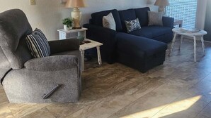 Una sala de estar con un sofá, un sillón y una mesita con una lámpara.