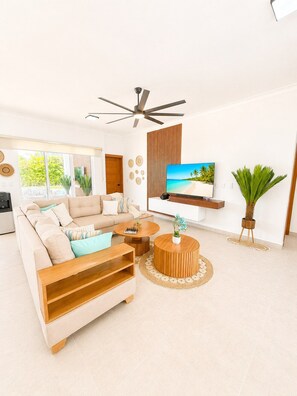 A modern living room with a sofa, coffee table, and TV. - 3bd with rooftop ocean view in Sosua Ocean Village (Sosúa)