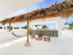 Une terrasse sur le toit, dotée d’un toit de chaume, d’un espace salon et offrant une vue sur l’océan.