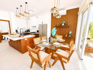 A modern kitchen with a central island, wooden chairs, and a dining table set for six. - 3bd with rooftop ocean view in Sosua Ocean Village (Sosúa)